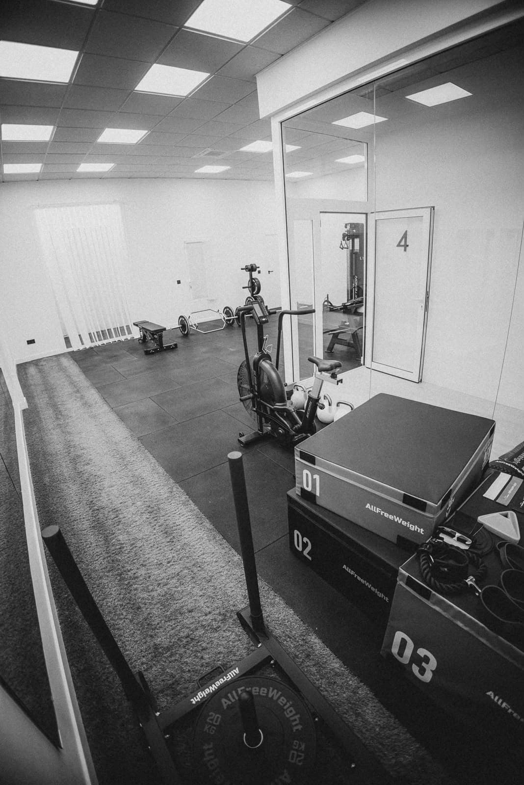 Zona de césped del gimnasio con trineo, bicicleta de aire y cajones de entrenamiento.